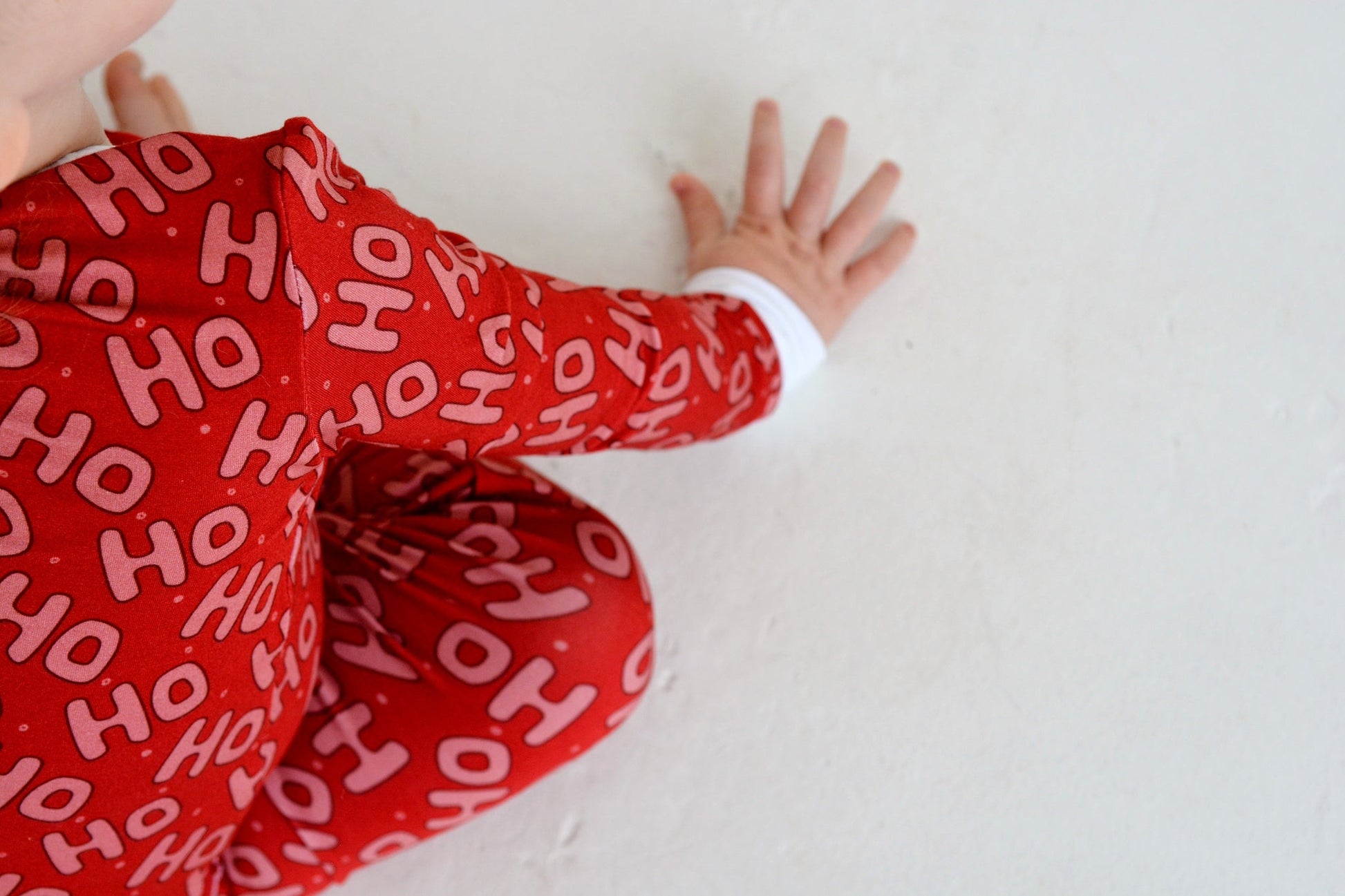 Baby in red Ho Ho Ho bamboo zippy pajamas with fold-over cuffs — soft 95% bamboo infant Christmas sleepwear | AddieGrey & Co